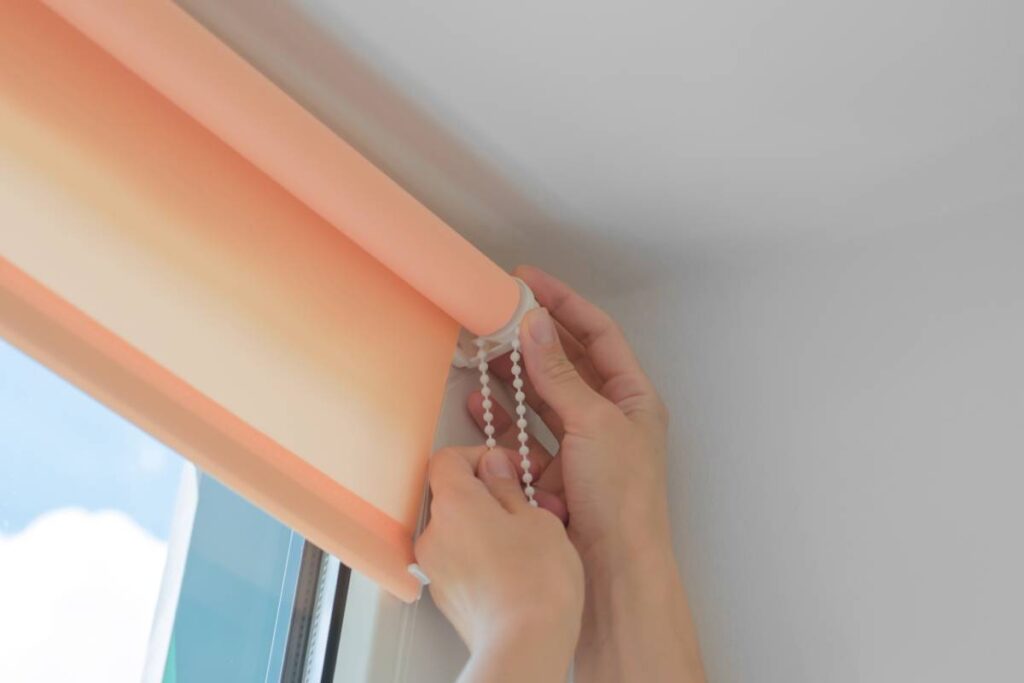 Installation of roller blinds. Close-up of female hands installing roller blinds on the window