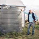 Man, portrait and water tank in farming liquid or soil hydration for vegetables, food and crops gro.