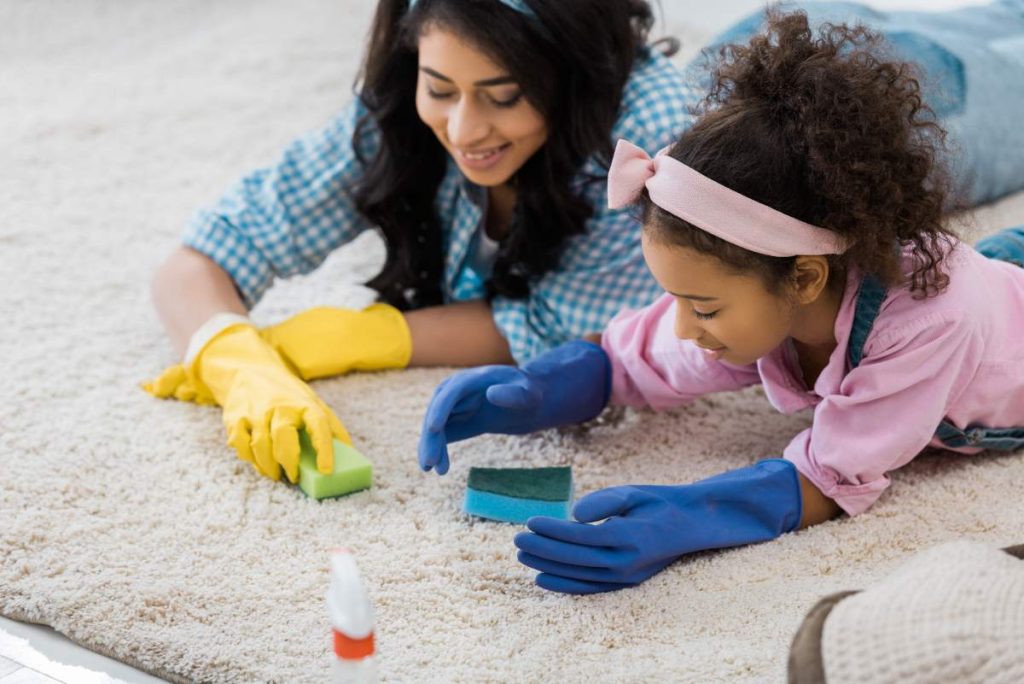 pretty african american woman with adorable daughter cleaning carpet with sponges